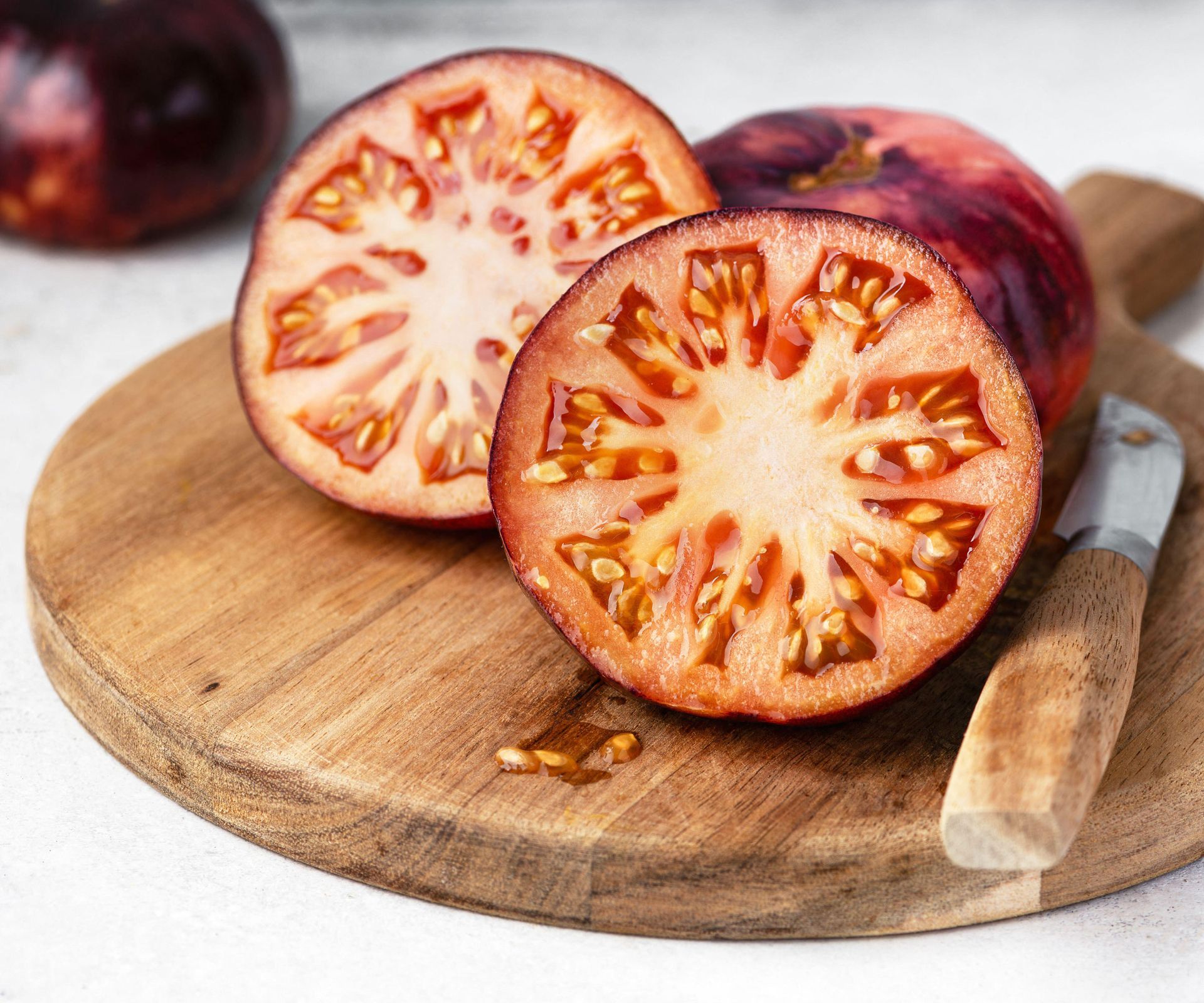 sliced purple tomatoes on chopping board with knife