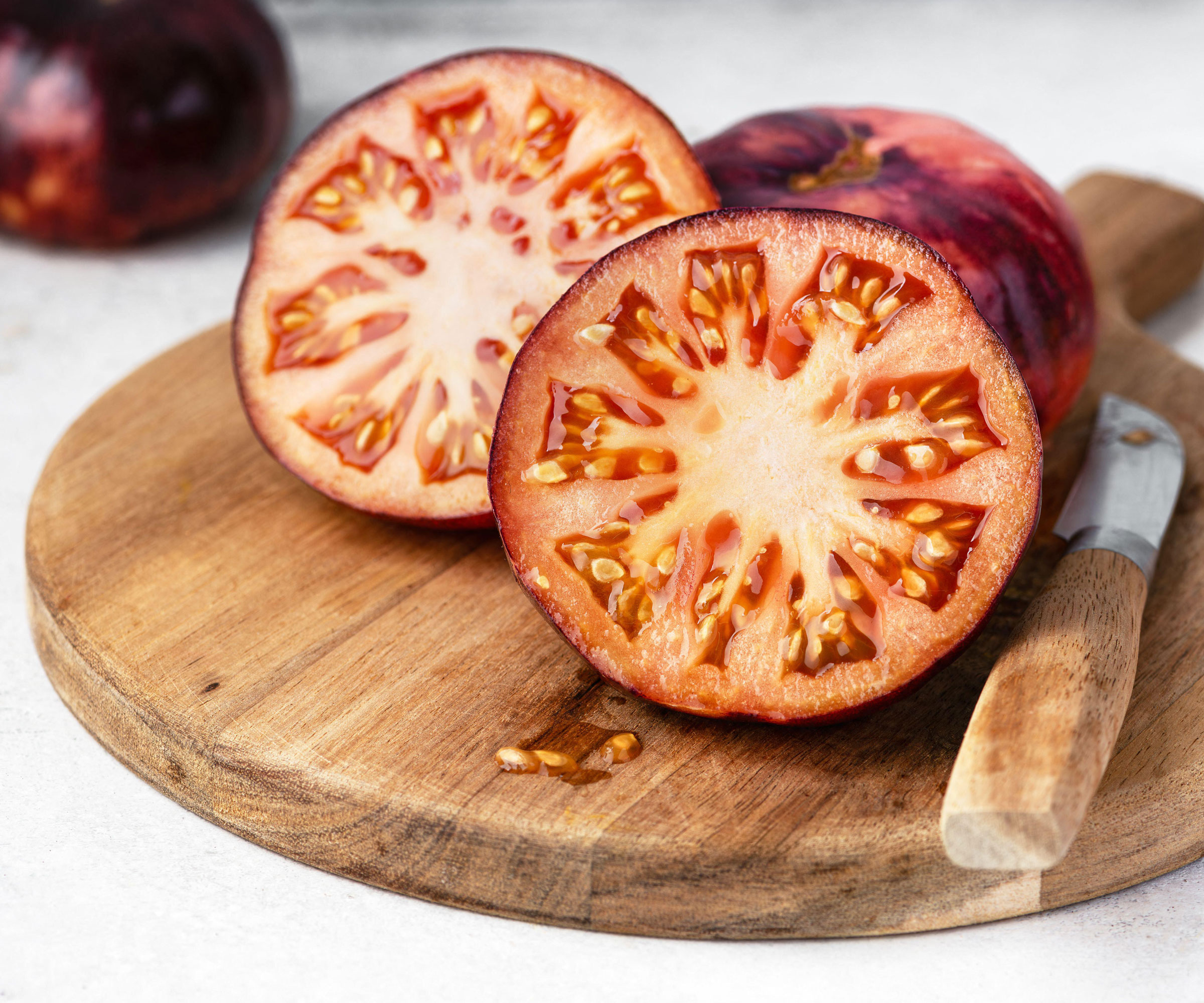 sliced purple tomatoes on chopping board with knife