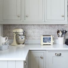 A grey kitchen with cream and silver kitchen appliances