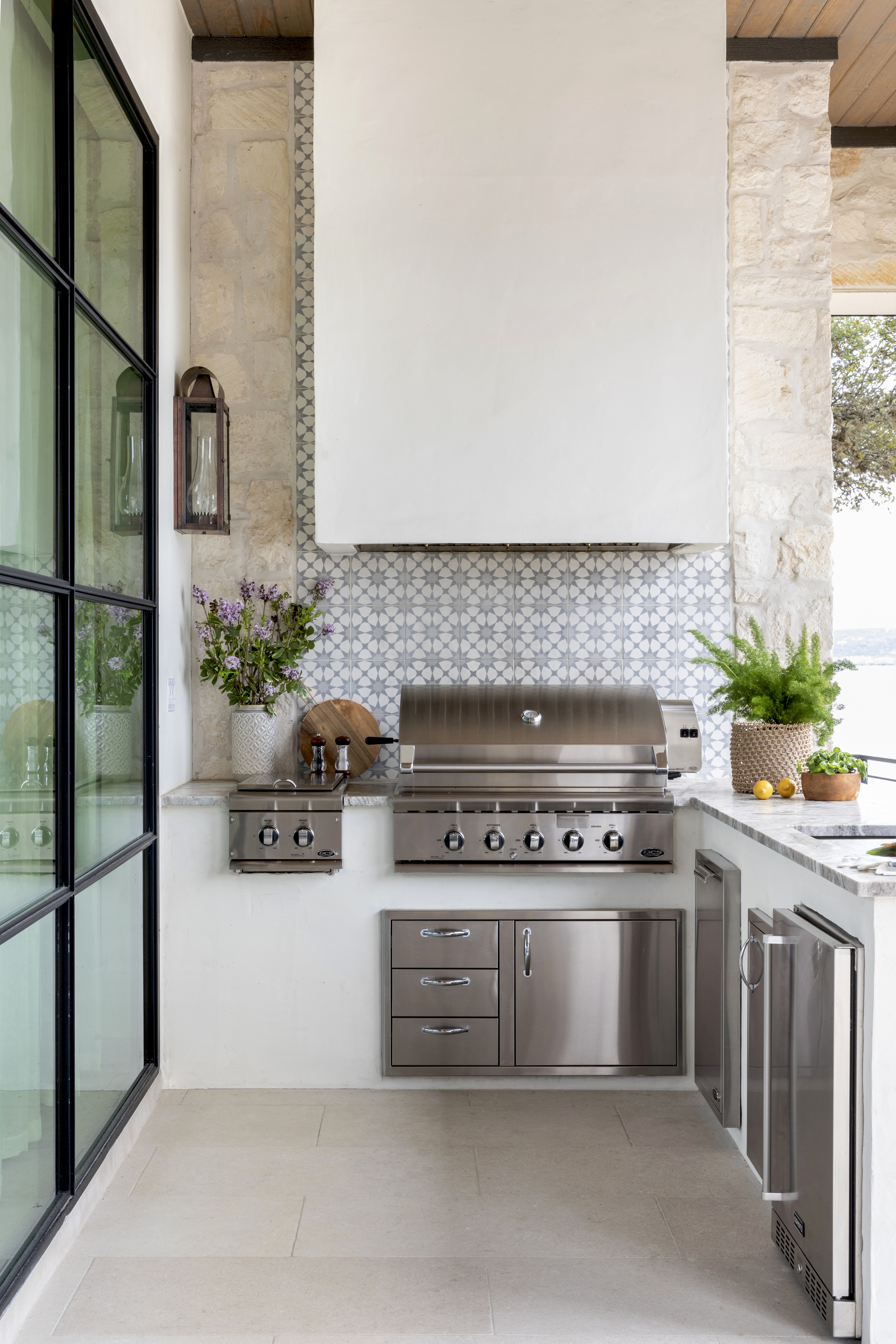 An outdoor space with a grill, that has a backsplash, a hood and storage