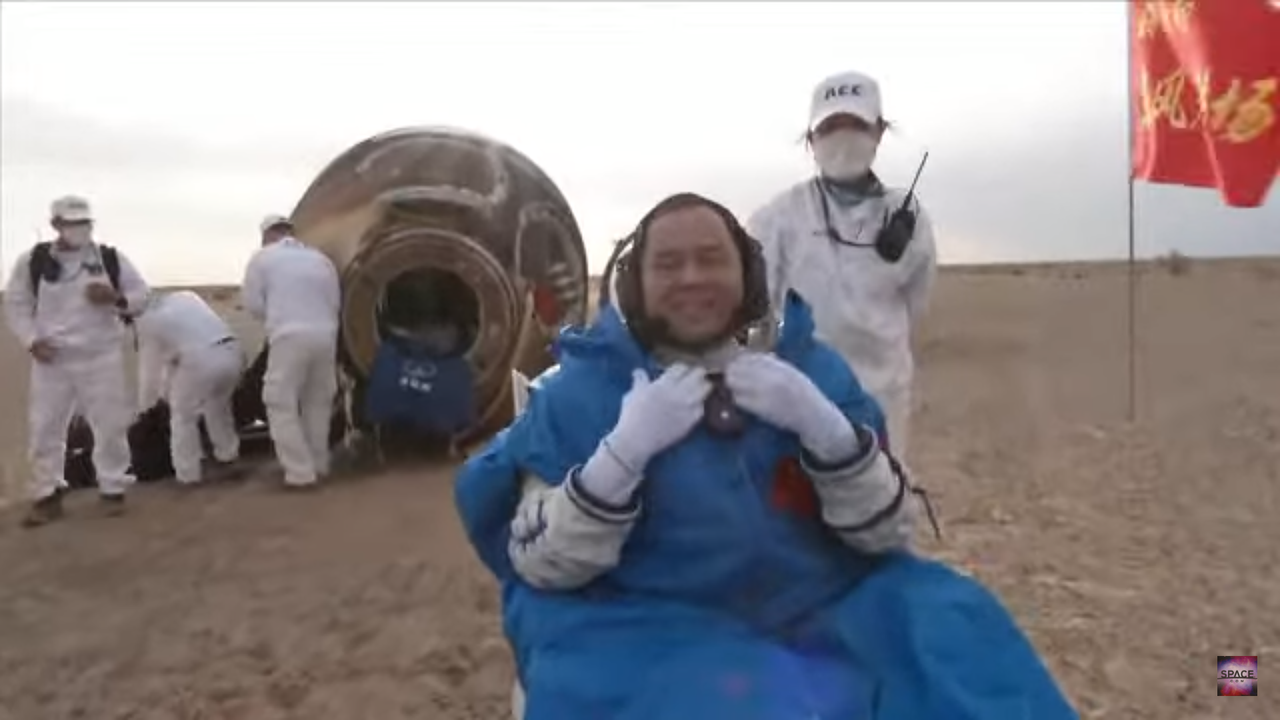 Shenzhou 15 astronaut Zhang Lu sits in front of his capsule with recovery teams