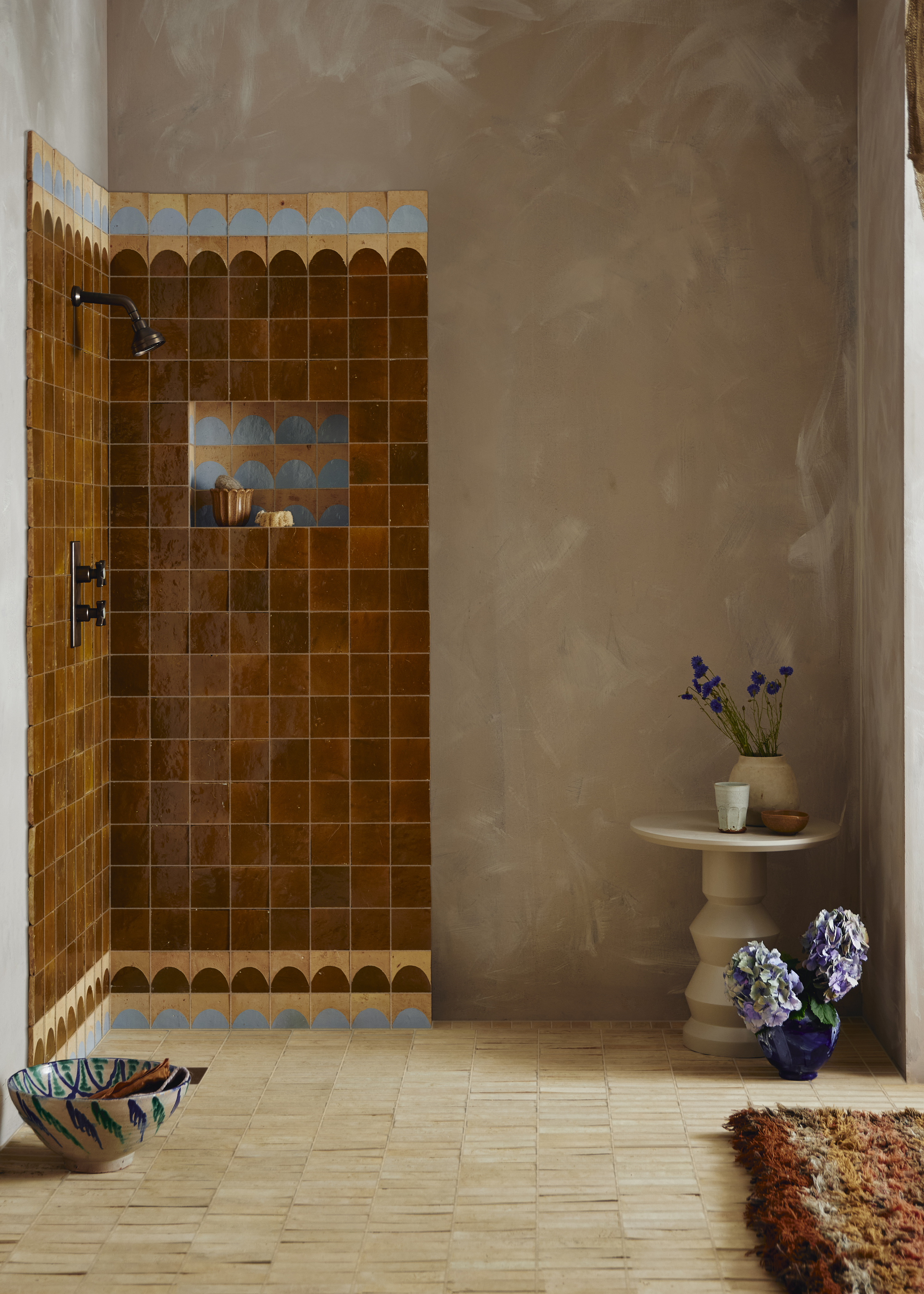 A bathroom with limewash walls and a shower with brown tiles