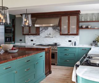 Blue kitchen with white marble countertops on the cabinetry and wooden countertops on the island