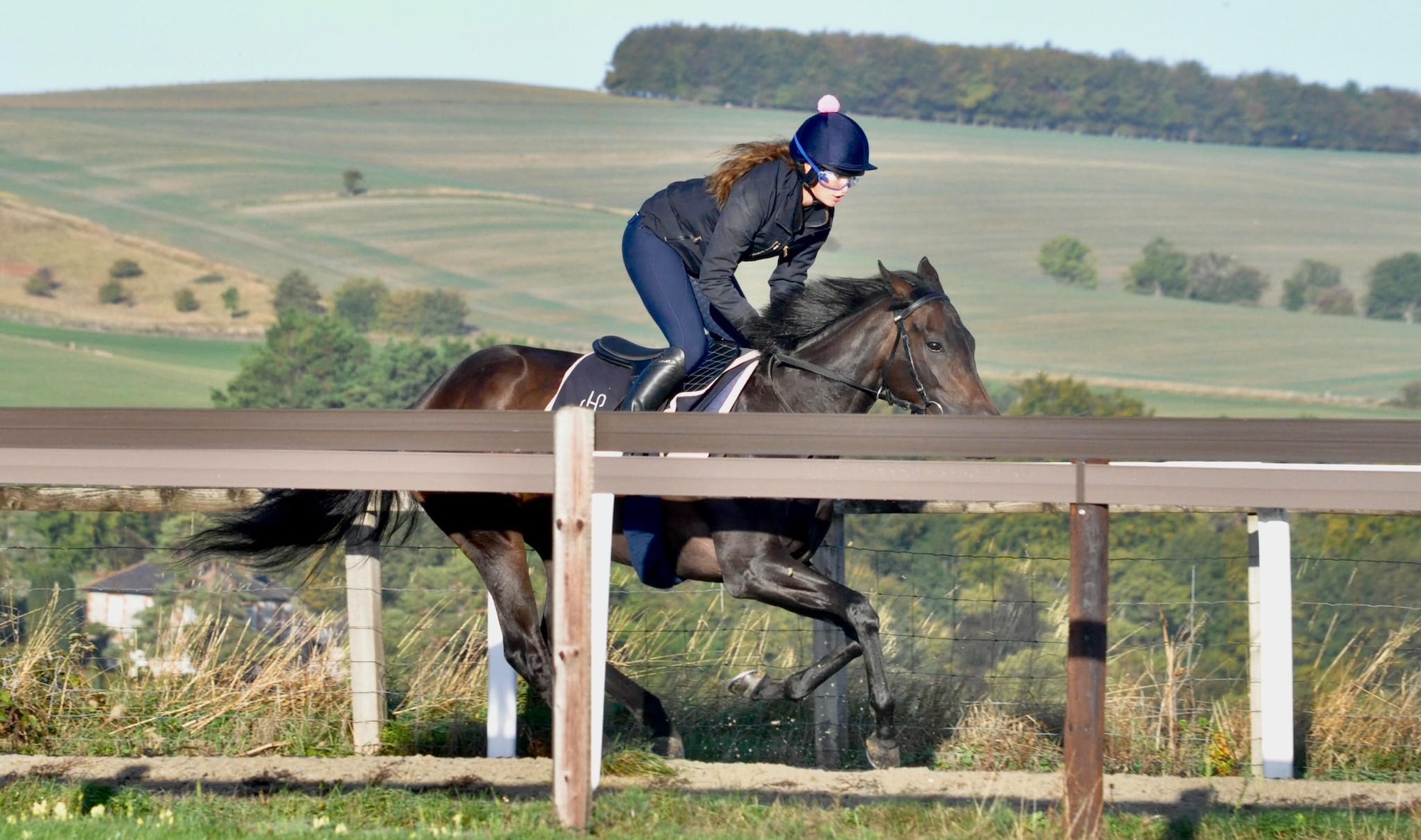 Tinks Walker riding a bay horse on the gallops