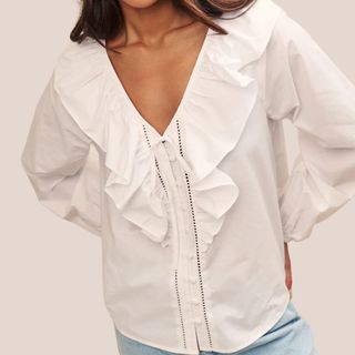 woman wearing white ruffle blouse and jeans 