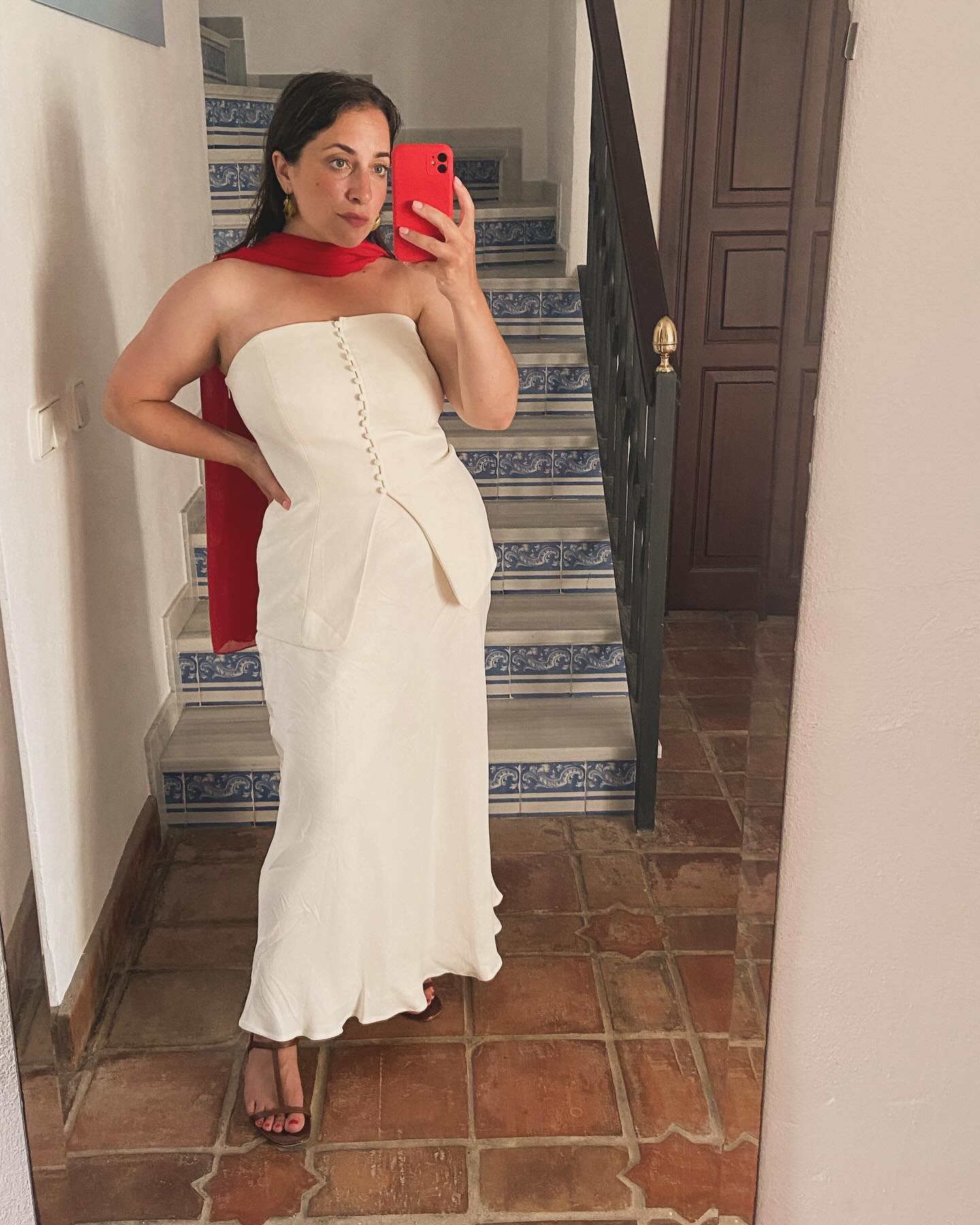 Woman wearing a white co-ord skirt and bustier with a red scarf