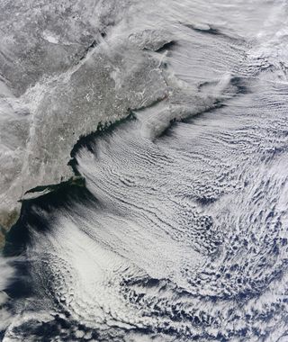 Cloud streets appear over the north Atlantic Ocean on January 24, 2011. These intriguing sky patterns appear when cold air blows over warmer waters, while a warmer air layer rests on top of both. Columns of heated, moist air rise into the atmosphere. The