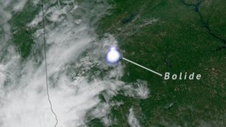 A bright dot next to a cloud over a green background