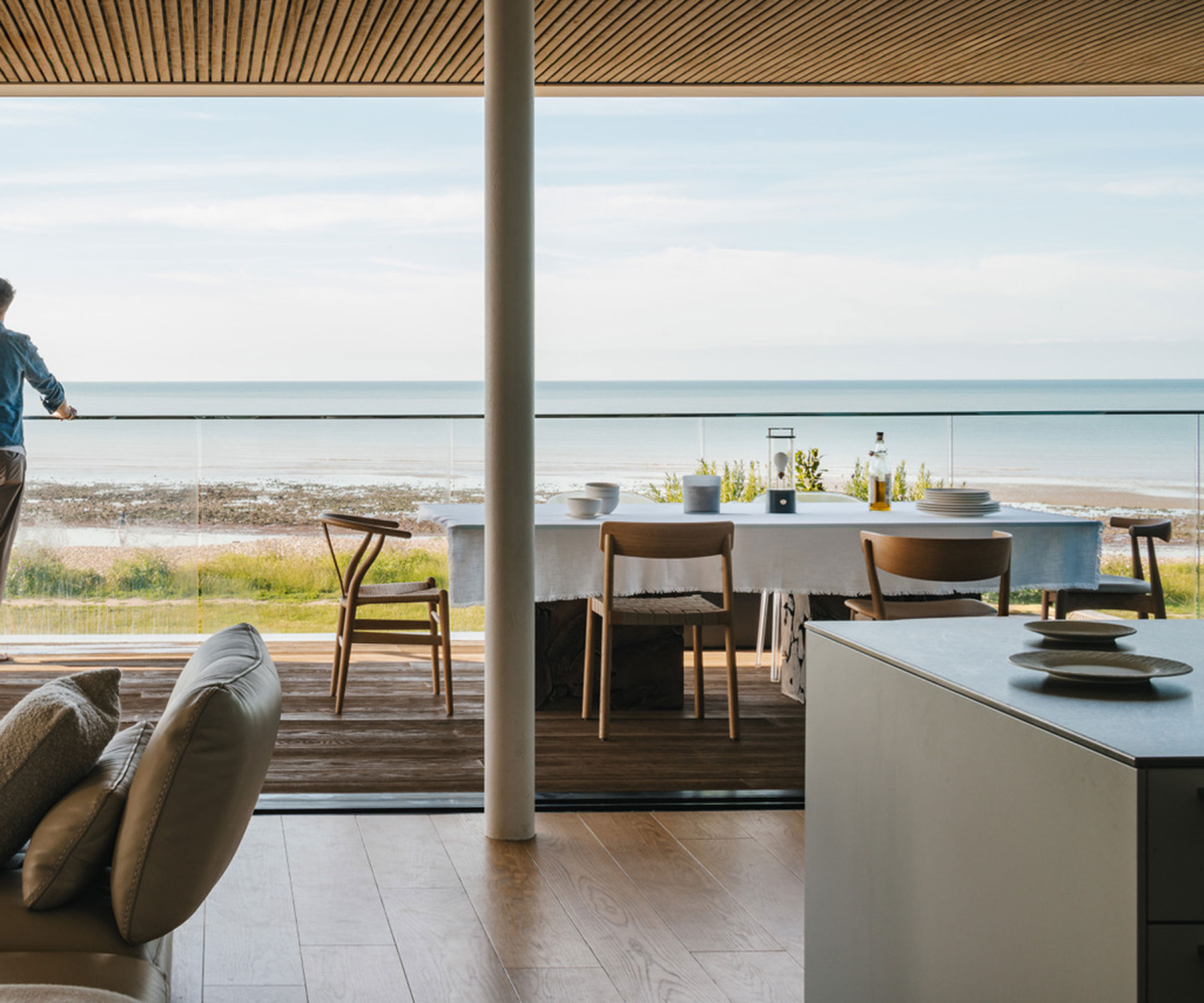 modern beach house with wall of sliding doors and balcony looking out to sea