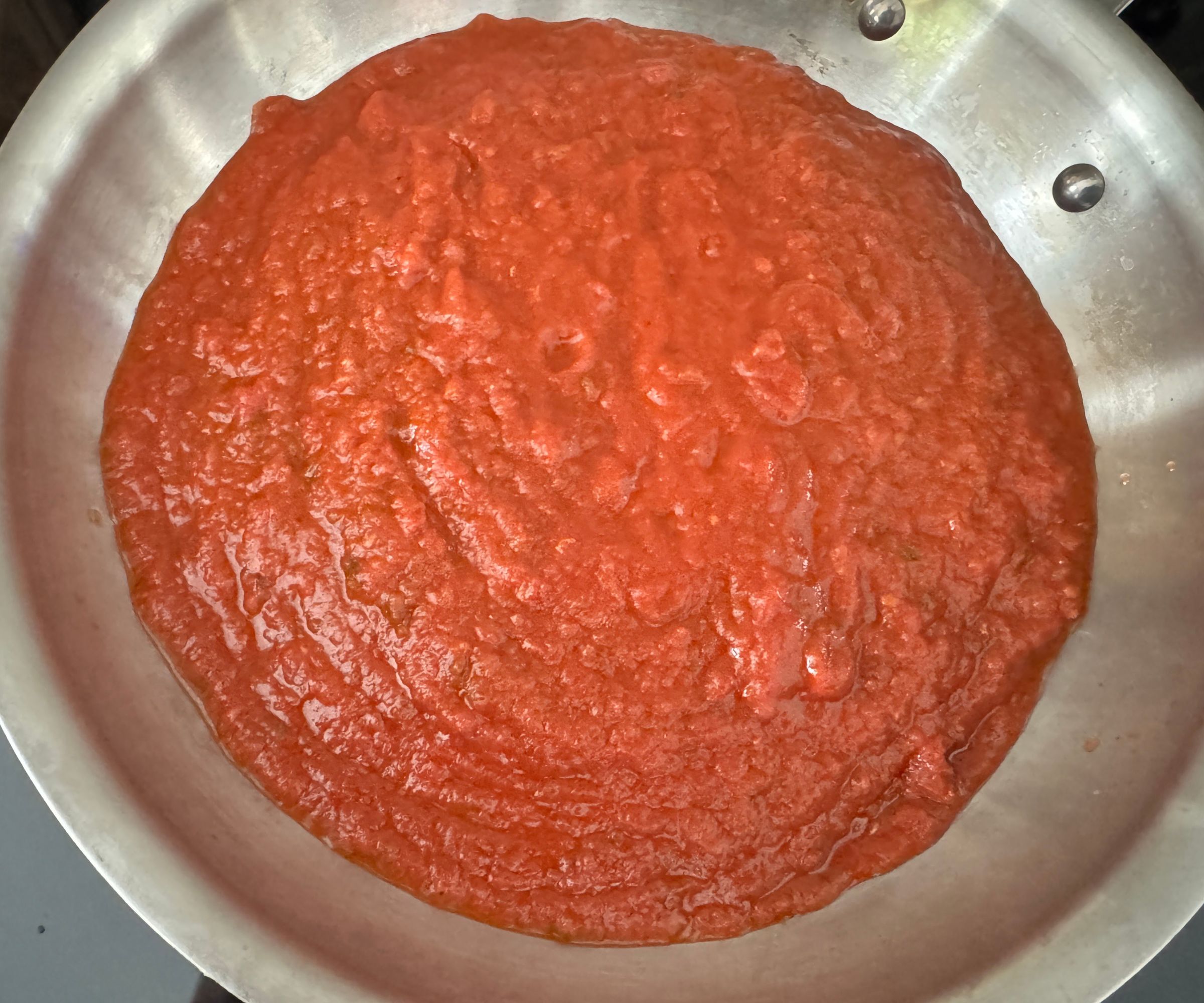Tomatoe sauce in a stainless steel pan, simmering. 