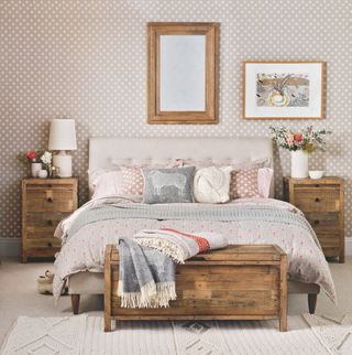 Bedroom with polka dot walls, upholstered bed, wooden ottoman and mirror