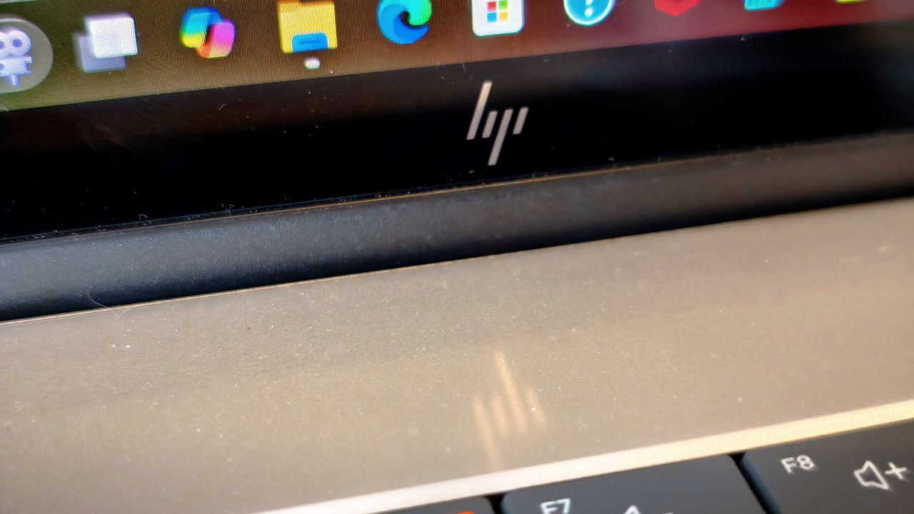 A silver HP Omnibook X Flip 16 2-in-1 laptop on a wooden desk