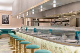 An old-style diner cafe features pastel-shaded decor in pale pink and seamarine with gold Art Deco accents.