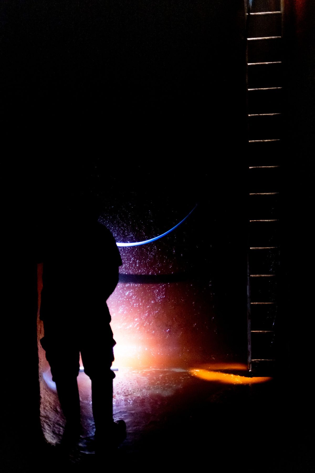 Silhouette of person inside empty wine vat using a headlamp.