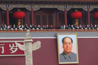 Xi Jinping stands above portrait of Mao Zedong.