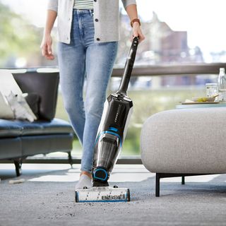 lady with balck with blue vacuum cleaner and black sofaset