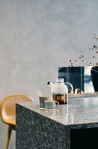 dark natural stone waterfall countertop in a minimalist kitchen