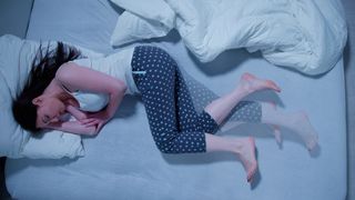 A person lying in bed with restless legs syndrome
