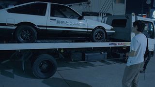 Takumi looks at his dad's white and black Toyota in Initial D
