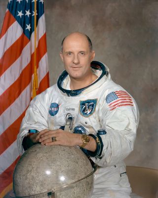 a man in a white spacesuit poses with a globe