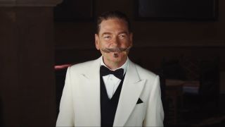 Kenneth Branagh smiling as he stands in a lobby in Death on the Nile.