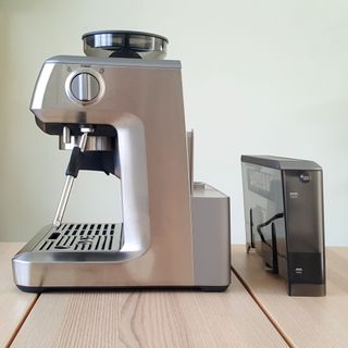 The Sage The Barista Express BES875UK Espresso Coffee Machine on a wooden table with its water tank removed