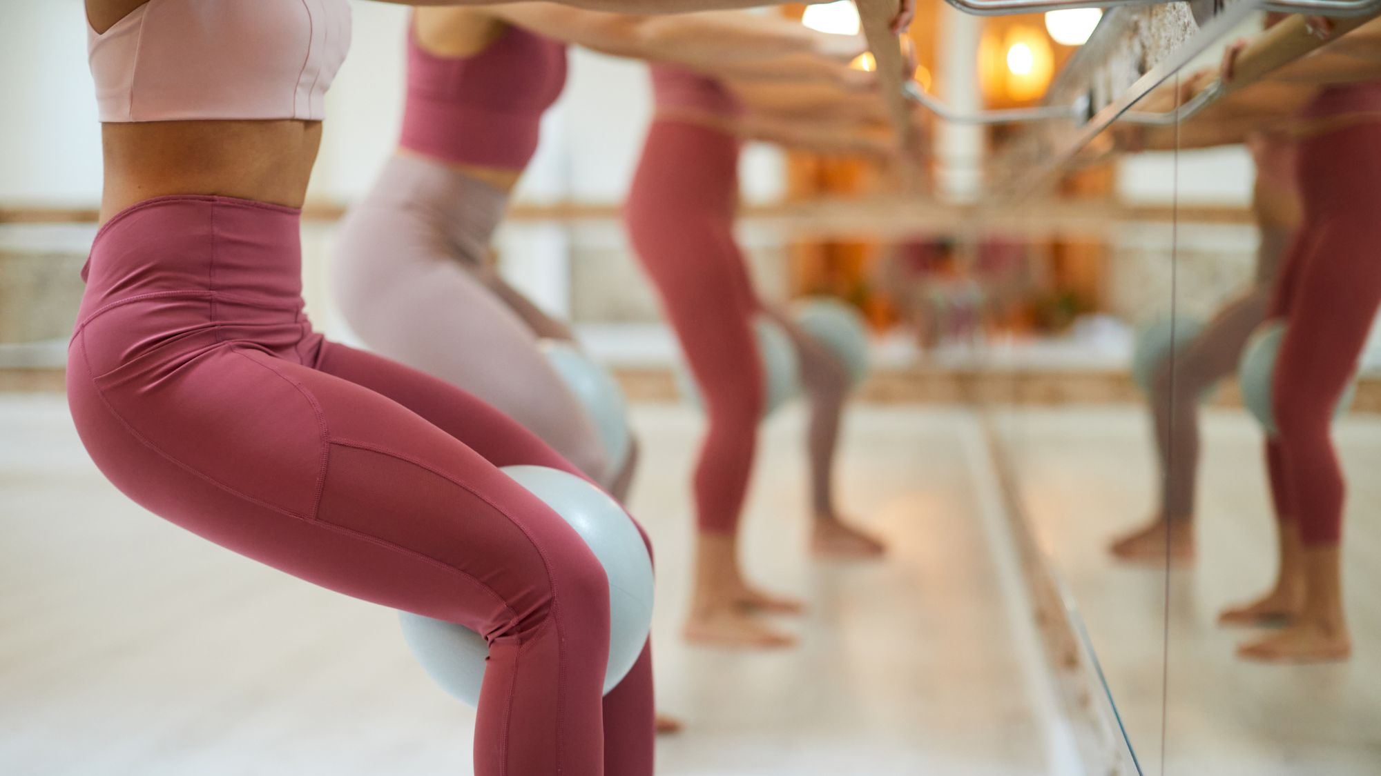 Four women doing some of the best Barre exercises in a studio with Pilates balls