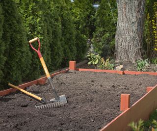 Rake and spade in a raised bed garden filled with soil