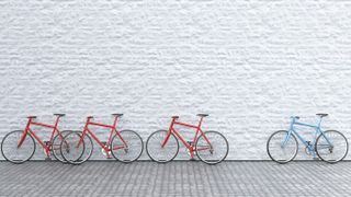 three red bikes and blue bike lined up against white wall