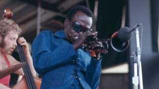 American trumpeter and composer Miles Davis (1926 - 1991) performing at the Newport Jazz Festival at Newport, Rhode Island, 4th July 1969. On the left is Dave Holland on bass.