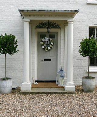 festive front door with wreath and potted bay trees