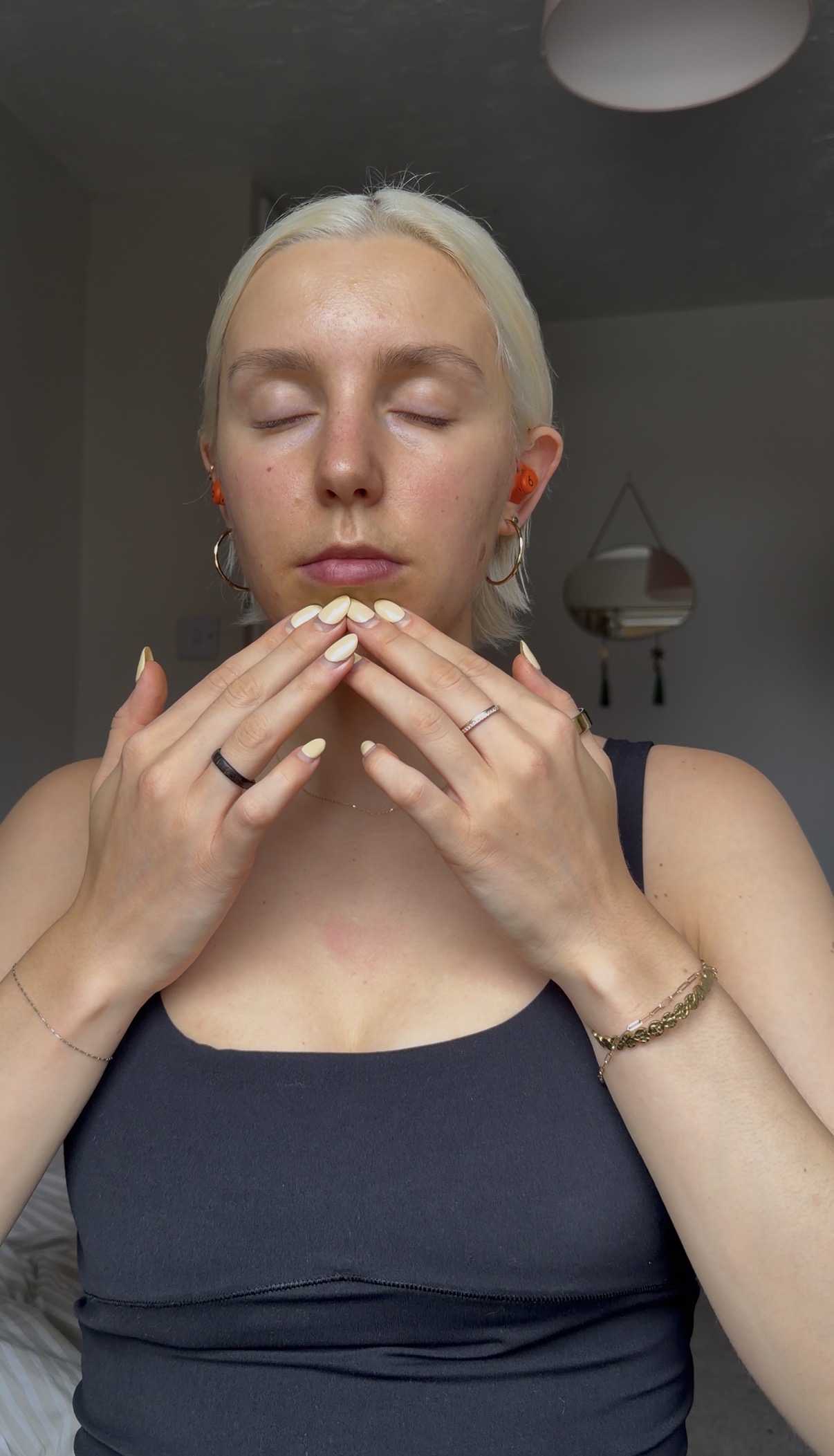 A woman practices a somatic therapy technique with her eyes closed and tapping on her chin