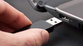 user inserting a USB flash drive into a laptop