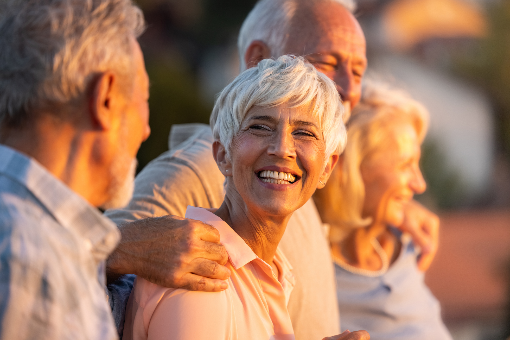 Happy mature woman talking to her friends while being embraced in nature.