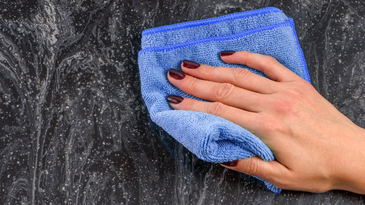 Cleaning the countertop. Caring for countertops in the kitchen or bathroom. Cleaning stone, marble or artificial stone countertops. Woman&#039;s hand wipes the surface of the marble countertop