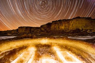 Pueblo Bonito at night with star paths.