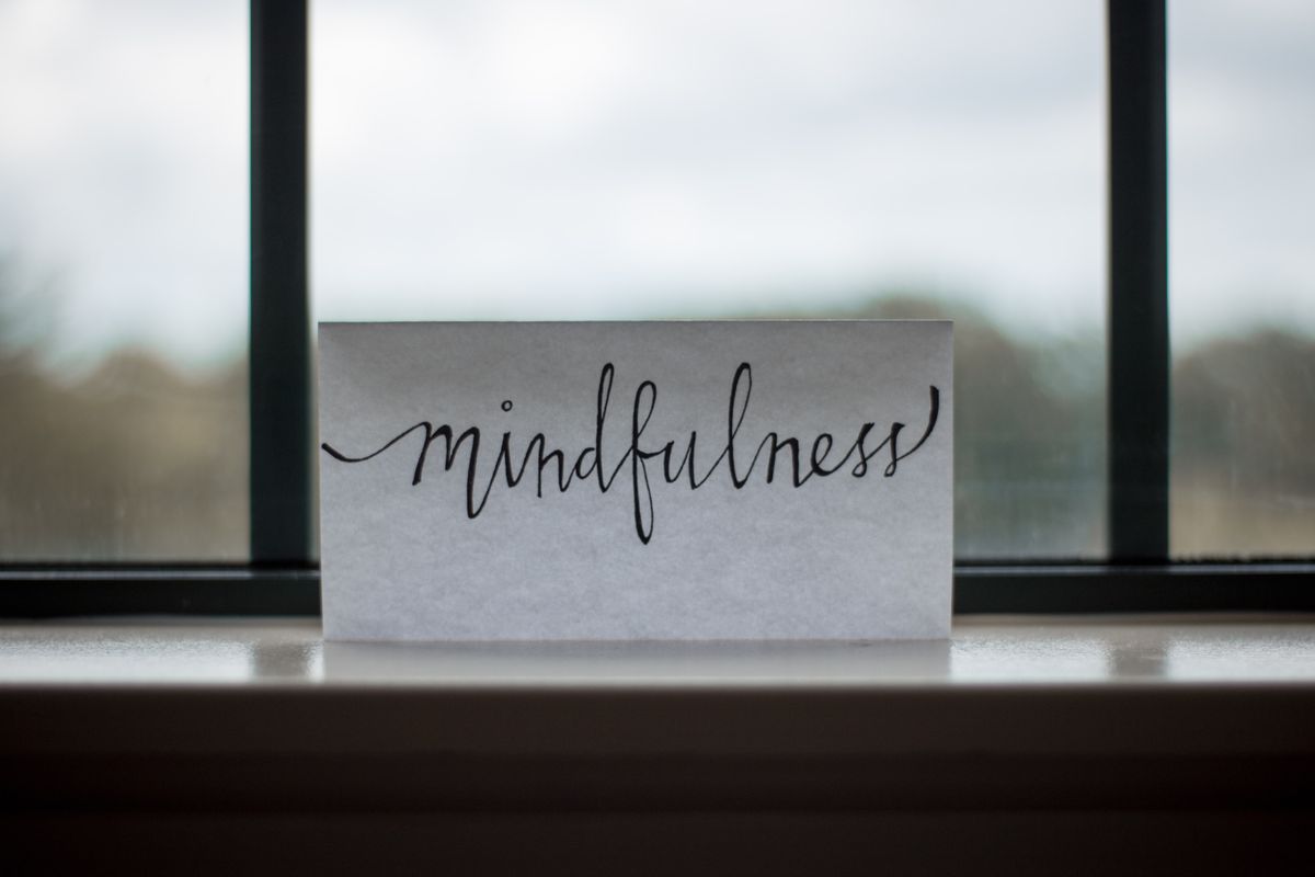 A piece of paper with the word &quot;mindfulness&quot; sits on a windowsill