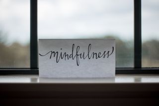 A piece of paper with the word "mindfulness" sits on a windowsill