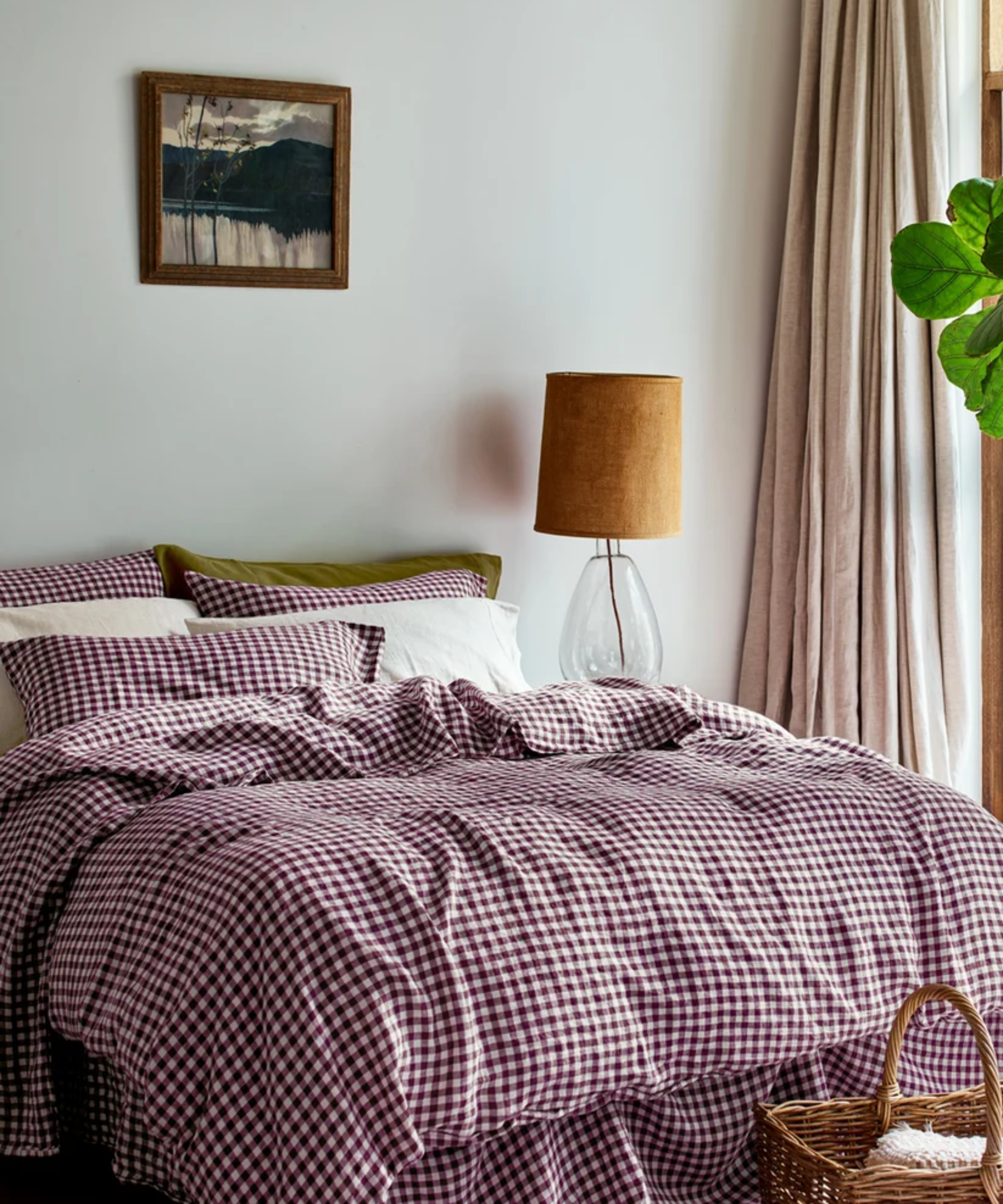 Cozy layered bedroom featuring natural beige drapes, wall art, and a bed styled with berry gingham sheets