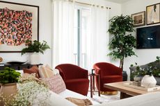 a living room with two armchairs and two sofas. Art is on the wall on one side, and a tv gallery wall is behind the sofa on the other