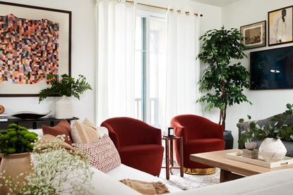 a living room with two armchairs and two sofas. Art is on the wall on one side, and a tv gallery wall is behind the sofa on the other