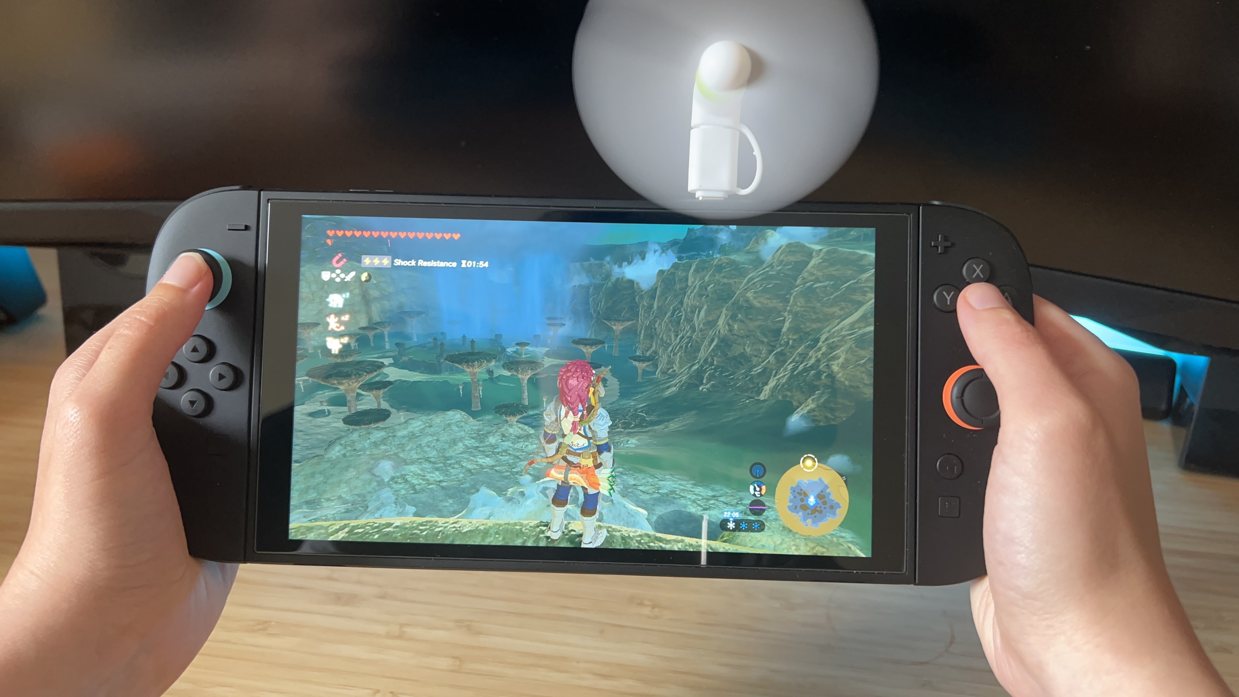 Hands holding Nintendo Switch 2 with a fan accessory while playing The Legend of Zelda: Breath of the Wild