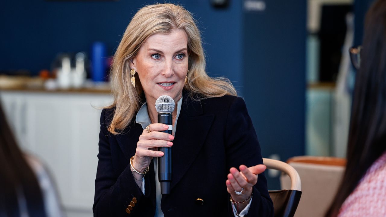 Duchess Sophie wearing a blue blazer speaking into a mic while sitting at a table