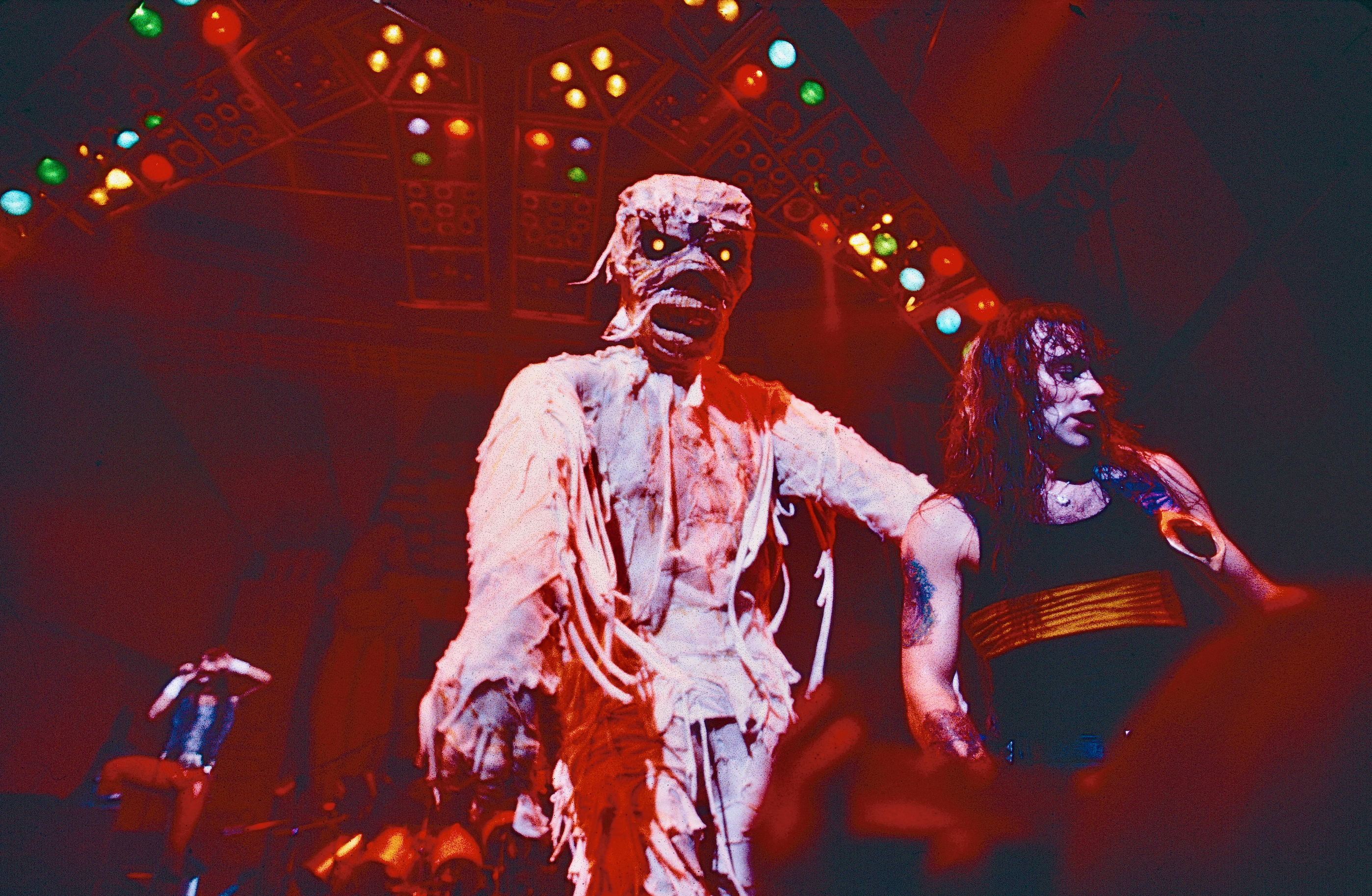 Steve Harris on stage in 1984 with a mummy Eddie looming over him