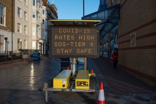 Sign saying, "Covid-19 rates high SOS tier 4 stay safe"