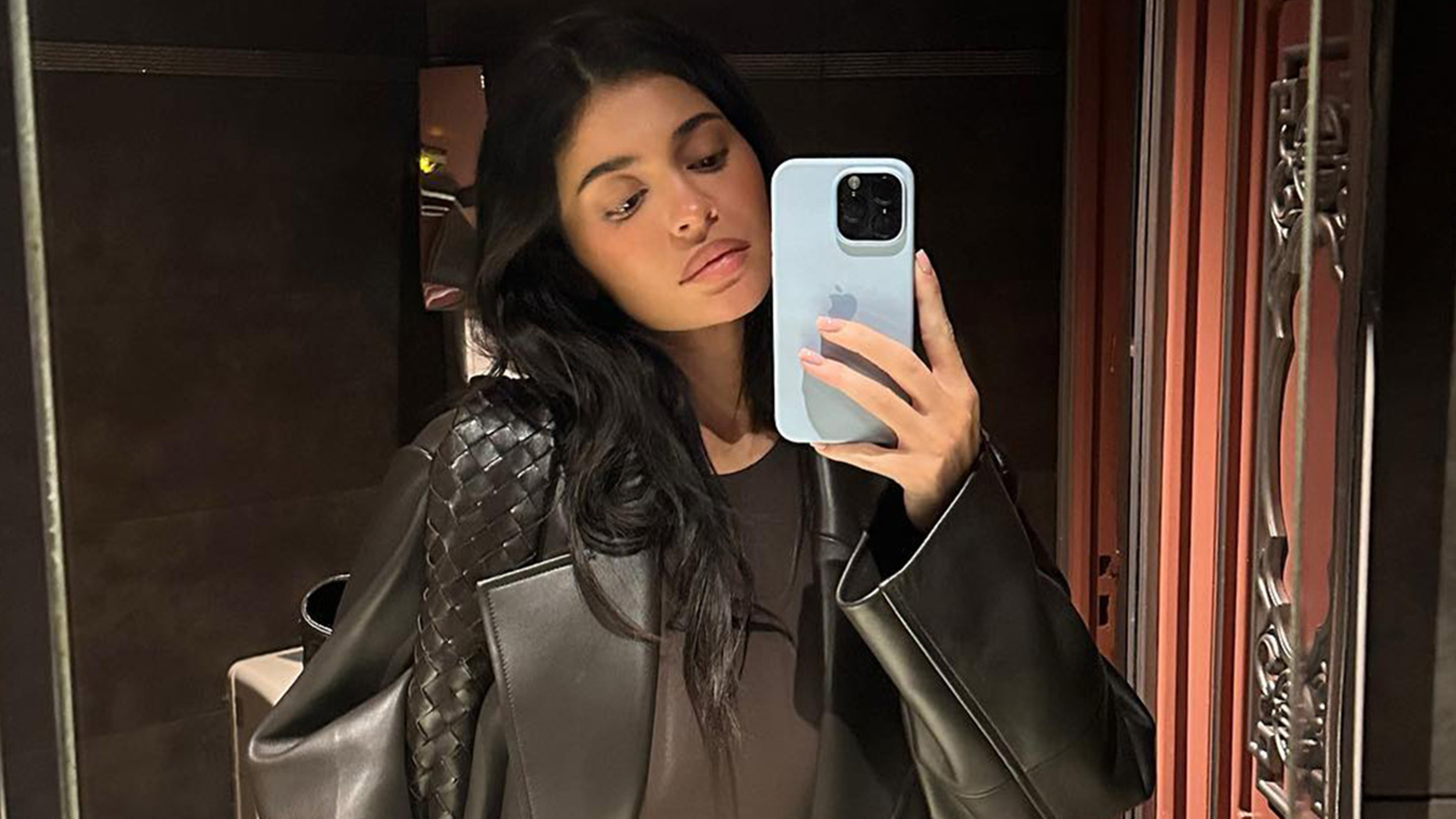 kylie wears a brown leather jacket and brown bottega veneta bag.