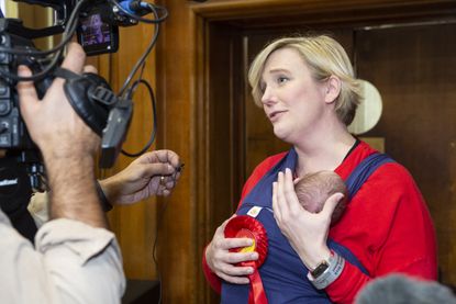 Stella Creasy being interviewed, holding a tiny baby