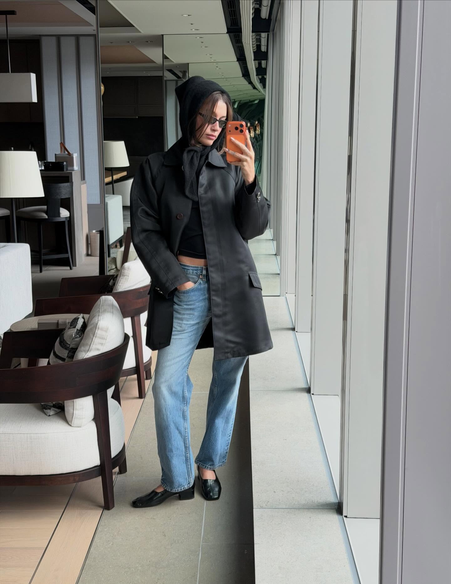 An image of @haileybieber wearing stovepipe jeans with a car coat and Reformation pumps.