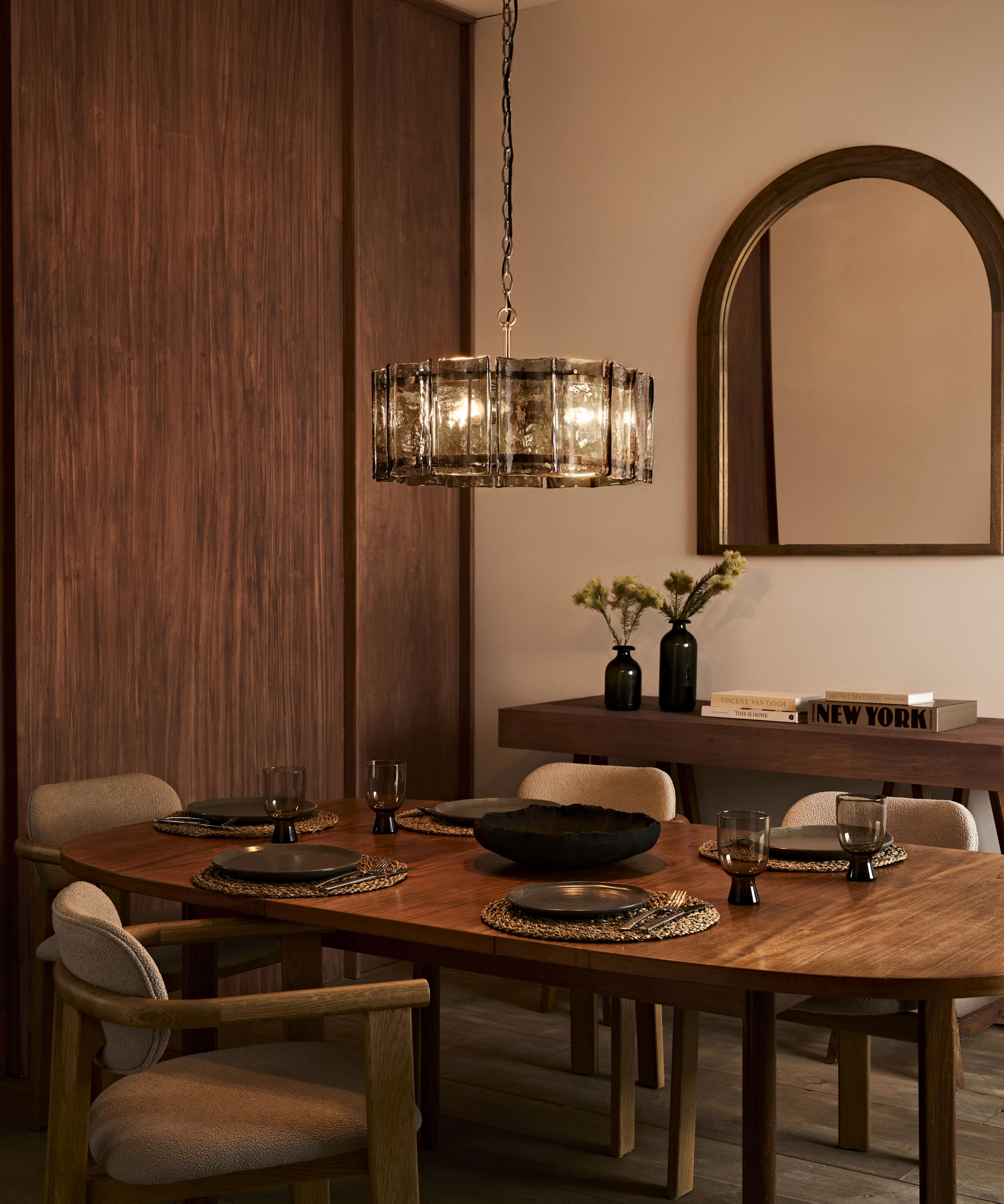glass and metal pendant light in dining room above walnut table and chairs
