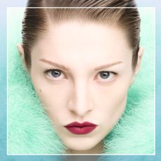 Hunter Schafer in a turquoise fluffy jacket wearing a bold red lipstick